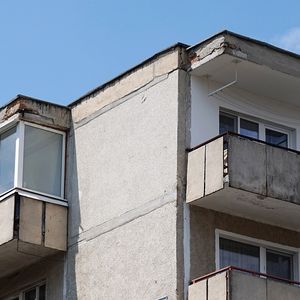 Bloc de locuințe cu un balcon închis cu geamuri lângă balcoane deschise