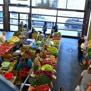 Comercianți de legume și fructe la mese, într-o hală de piață agroalimentară din România