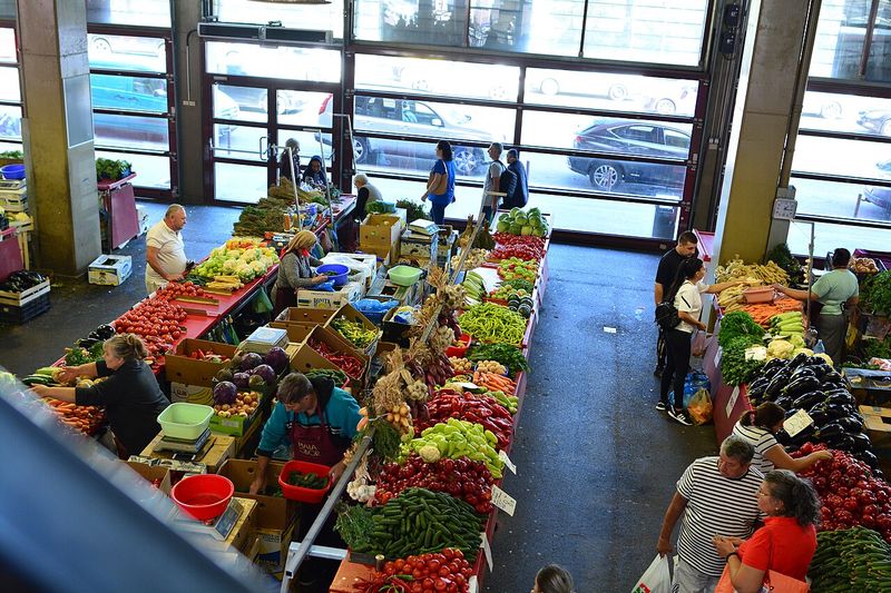 Comercianți de legume și fructe la mese, într-o hală de piață agroalimentară din România